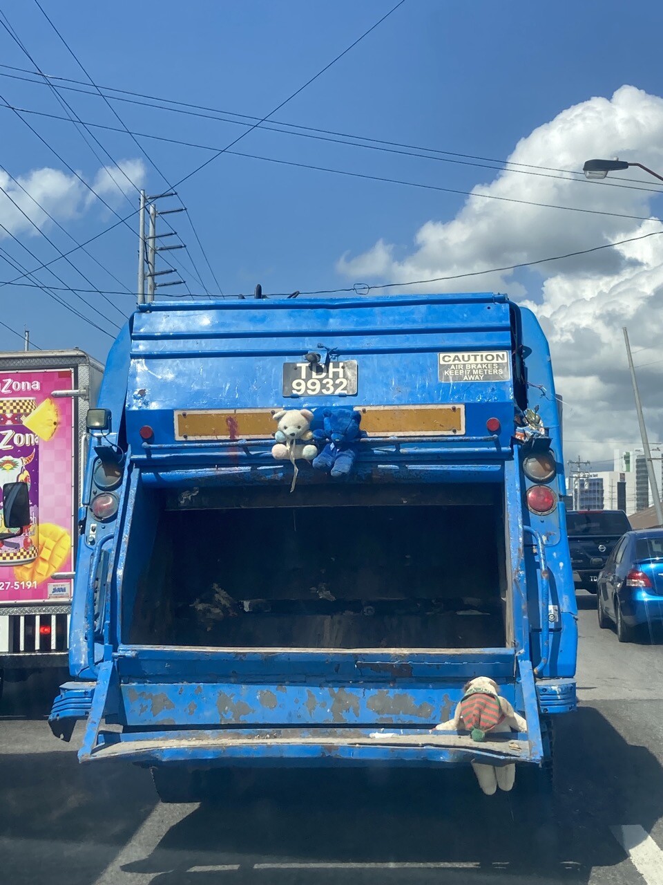 Behind a garbage truck with stuffed toy animals (teddy bears and a turtle)